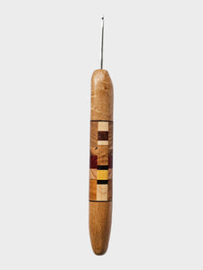 Wooden crochet hook with a multicolored handle on a light gray background
