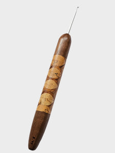 Wooden crochet hook with decorative pattern on a light gray background