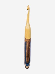 Wooden crochet hook with a dark wood handle on a light blue background