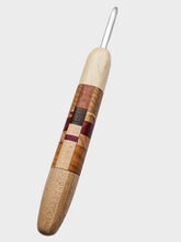 Wooden crochet hook with a metal eye on a light gray background