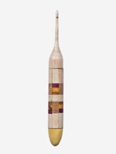 Wooden crochet hook with multicolored handle on a light gray background