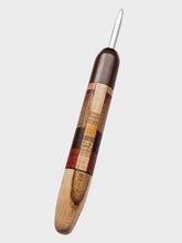 Wooden crochet hook with multicolored pattern on a light gray background