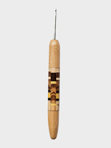 Wooden crochet hook with a metal tip on a light gray background