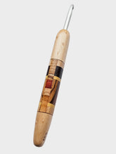 Wooden crochet hook with metal eye on a light gray background