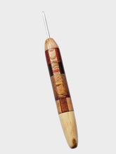 Wooden crochet hook with a metal tip on a gray background