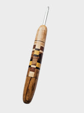 Wooden crochet hook with a checkered pattern on a gray background