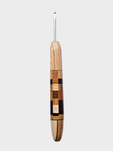 Wooden crochet hook with a metal end on a light gray background