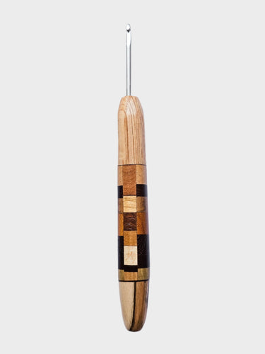 Wooden crochet hook with a metal end on a light gray background