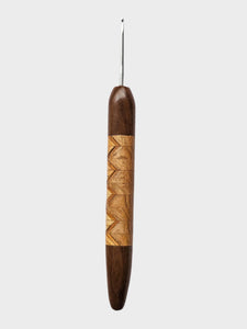 Wooden crochet hook with decorative pattern on a light gray background
