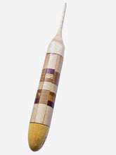 Wooden crochet hook with a striped handle on a light gray background